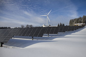 Solar panels and wind turbine in a snowy landscape, showcasing renewable energy sources. HD wallpaper