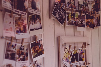 Collection of vintage Polaroid clipped to a wooden wall indoors. HD wallpaper
