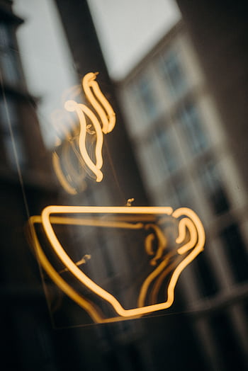 A glowing neon coffee cup sign with a blurred urban backdrop evokes a cozy café vibe. HD phone wallpaper