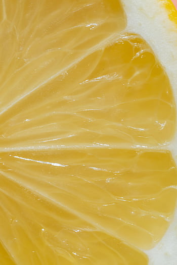 Detailed macro shot of a vibrant lemon slice showcasing juicy pulp and vibrant color. HD phone wallpaper