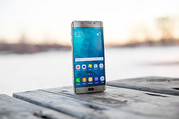 Samsung smart placed on a wooden surface outdoors during sunset. HD wallpaper