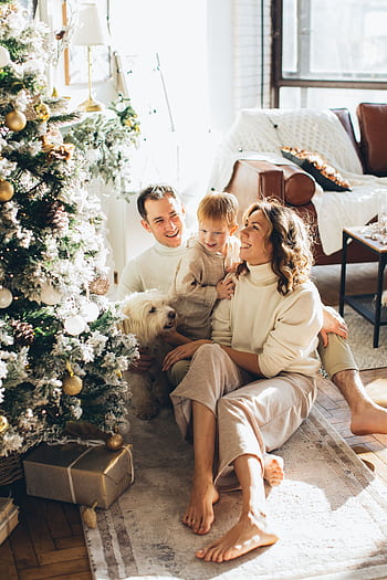 A happy family celebrating Christmas morning with a decorated tree and gifts. HD phone wallpaper
