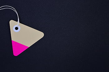 Triangular cardboard tag with vibrant pink and beige hues on a black background, perfect for design use. HD wallpaper