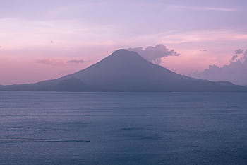 A breathtaking view of a sunset over Lake Atitlán in Guatemala with a volcano silhouette. HD wallpaper