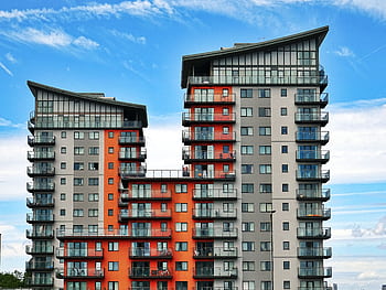 Modern high-rise apartment buildings with unique architecture under a vibrant blue sky. HD wallpaper