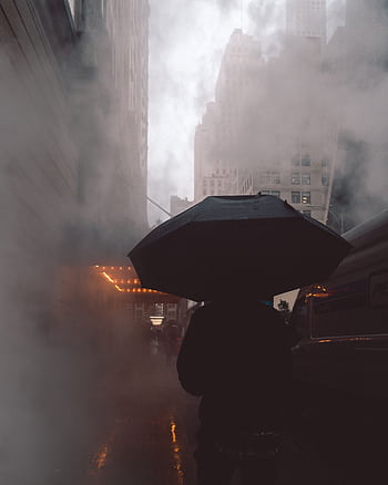 A mysterious silhouette with an umbrella on a foggy street in Queens, NY, showcasing urban life. HD phone wallpaper