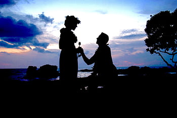 A couple's silhouette during a romantic sunset beach proposal, capturing love at twilight. HD wallpaper
