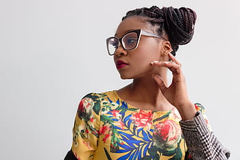 Elegant portrait featuring a woman in glasses with braided hairstyle and floral top. HD wallpaper