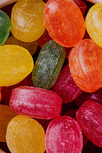 Top view of vibrant multicolored hard candies, perfect for festive and holiday themes. HD phone wallpaper