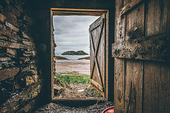 A rustic wooden doorway frames a que beach view with an island in the distance. HD wallpaper
