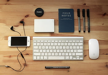 Top view of a modern desk setup featuring electronics, stationery, and gadgets on a wooden surface. HD wallpaper