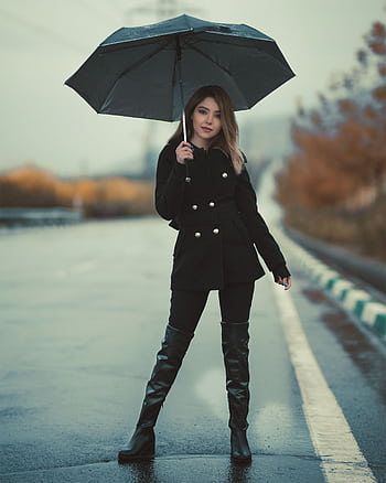 Chic woman dressed in fashionable attire holding an umbrella on a rainy street. HD phone wallpaper