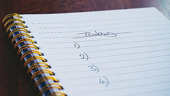 A close-up view of a handwritten to-do list on a spiral notebook with numbers for tasks. HD wallpaper