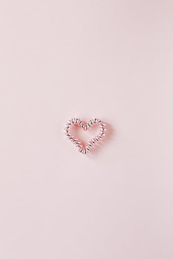 Elegant minimalist of a heart-shaped coil on a light pink background, perfect for Valentine's Day themes. HD phone wallpaper