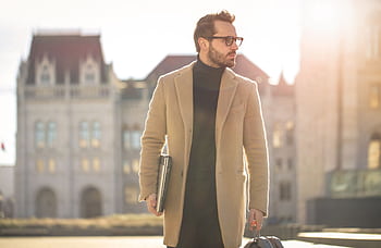 Fashionable young man with a laptop walking in the sunlight near a historic building in Budapest. HD wallpaper