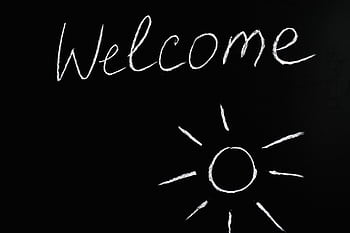 Chalk-drawn 'Welcome' and sun illustration on a black chalkboard background. HD wallpaper