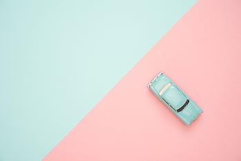 Toy car on a pastel pink and blue background, representing simplicity and retro design. HD wallpaper