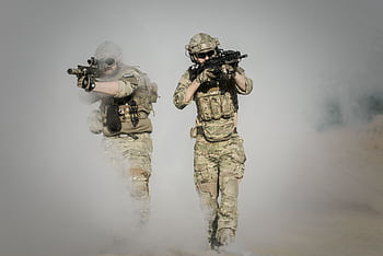 Two soldiers in camo uniforms with weapons advancing through a smoke-covered field, showcasing military action. HD wallpaper