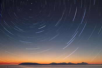 A stunning long exposure of star trails over the ocean horizon at twilight. HD wallpaper