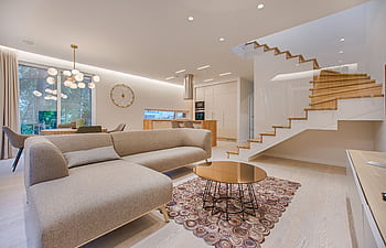 Contemporary living room with neutral tones, a sleek sofa, and elegant wooden staircase. HD wallpaper