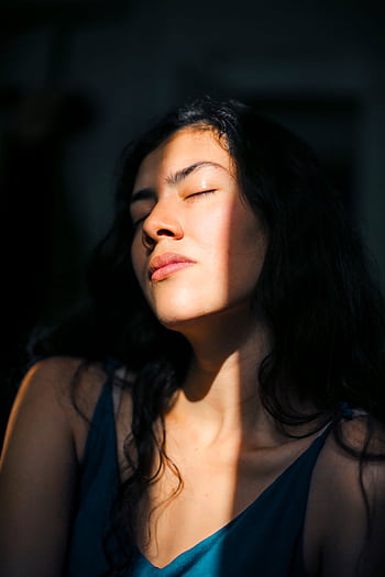 Close-up portrait of a woman with eyes closed, bathed in soft sunlight and shadows. HD phone wallpaper