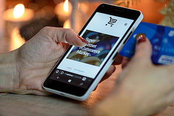 Woman using smart for online shopping with credit card in hand, festive background lighting. HD wallpaper