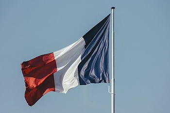 The French national flag waving against a bright blue sky, symbolizing liberty and national pride. HD wallpaper