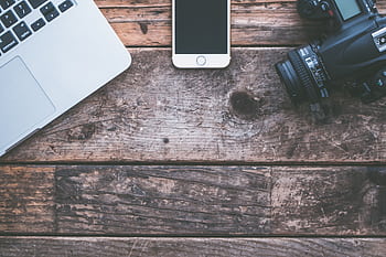 Flat lay of rustic wooden desk with laptop, smart, and camera. HD wallpaper