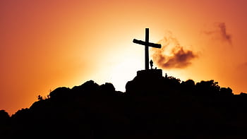 Majestic silhouette of a cross on a hill during a vivid sunset, symbolizing spirituality. HD wallpaper