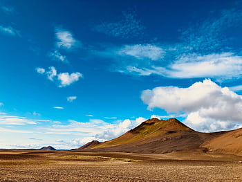Stunning Icelandic landscape featuring rugged mountains under a vibrant blue sky and fluffy clouds. HD wallpaper
