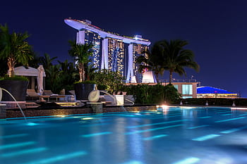 Illuminated Marina Bay Sands hotel above pool at night, capturing Singapore's iconic skyline. HD wallpaper