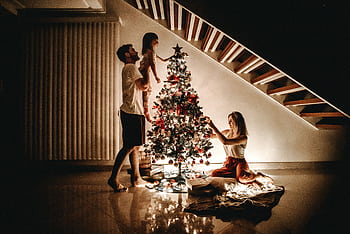 A family decorates a Christmas tree, bringing warmth and joy to the holiday season. HD wallpaper