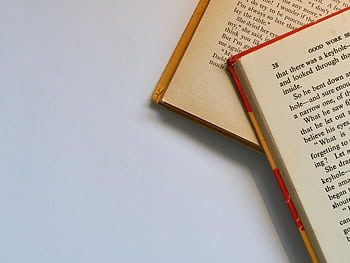 Top view of open books with visible pages and text on a clean white background. HD wallpaper