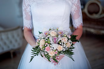 Close-up of a bride holding a delicate bouquet with white and pink flowers in a lace wedding dress. HD wallpaper