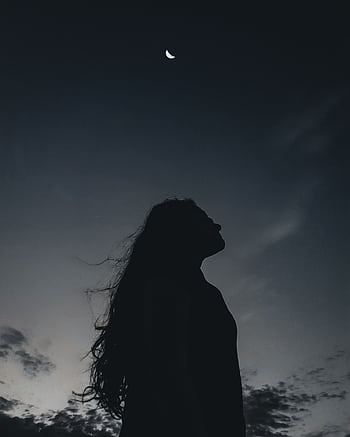 A striking silhouette of a woman gazing at a crescent moon in a dark twilight sky, evoking a sense of mystery. HD phone wallpaper