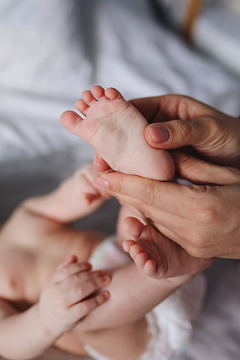 A close-up of a parent's hands gently massaging a baby's feet, showcasing tenderness and care. HD phone wallpaper