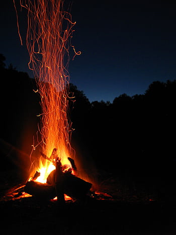 A vibrant campfire with sparks rising against a serene night backdrop, ideal for outdoor themes. HD phone wallpaper