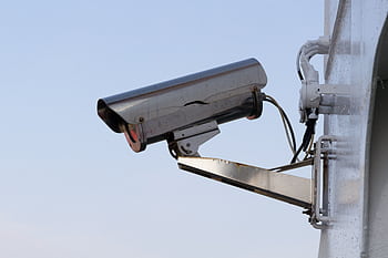Close-up of an outdoor CCTV camera installed on a wall for security purposes. HD wallpaper