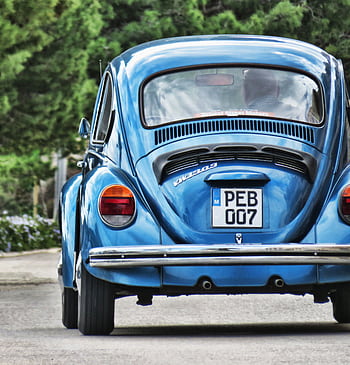 Classic blue Volkswagen Beetle driving on a scenic road. HD phone wallpaper