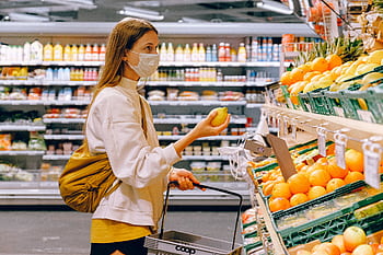 A woman wearing a face mask shops for fruits in a supermarket during a pandemic. HD wallpaper