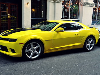 A stylish yellow Chevrolet Camaro parked on a city street, showcasing its sporty design. HD wallpaper