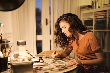 A young woman artist concentrating on a painting project inside her studio. HD wallpaper