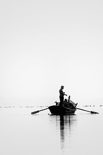 Monochromatic capturing a lone fisherman in a boat on calm waters, creating a serene silhouette. HD phone wallpaper