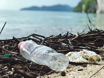 Discarded plastic bottle on a Malaysian beach, highlighting environmental pollution. HD wallpaper