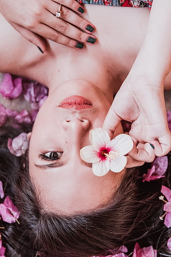 Elegant hoot featuring a woman holding a pink flower amidst petals. HD phone wallpaper