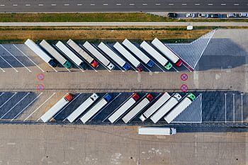 Overhead shot of semi-trucks parked in Poznań, Poland, demonstrating transportation logistics. HD wallpaper