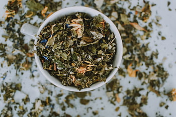 Overhead shot of a cup with a blend of dried herbal tea leaves and flowers. HD wallpaper