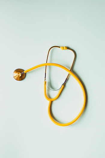 A vibrant yellow stethoscope on a pastel green backdrop, symbolizing healthcare. HD phone wallpaper