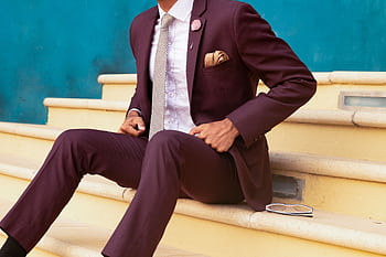 Elegant man in a burgundy suit sitting on steps, exuding sophistication and style. HD wallpaper