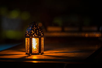 A glowing lantern with crescent motifs creates a warm ambiance for Ramadan or Eid. HD wallpaper
